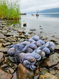 Coloris Inverness de la collection Outyarnder inspiré par la série culte. Photo prise avec les écheveaux en stellina gold de couleurs bleu lavande, moutard, marron-nour. Photo prise devant le Loch Ness en Ecosse